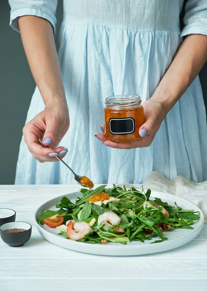 Kavanoz soslu roka ve karides salatası sulayan kadın.