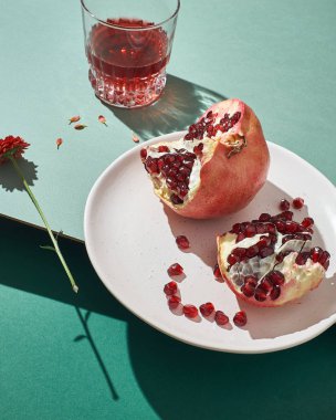 Dilimlenmiş nar ve meyve suyu ile bardaklar. Yeşil arka planda hayat.