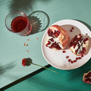 Dilimlenmiş nar ve meyve suyu ile bardaklar. Yeşil arka planda hayat.