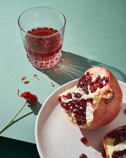 Sliced pomegranates and glasses with juice - still life on a green background — Stock Photo, Image