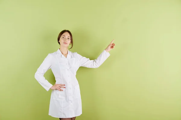 Médica de pele branca com um casaco branco aponta a mão para algo — Fotografia de Stock
