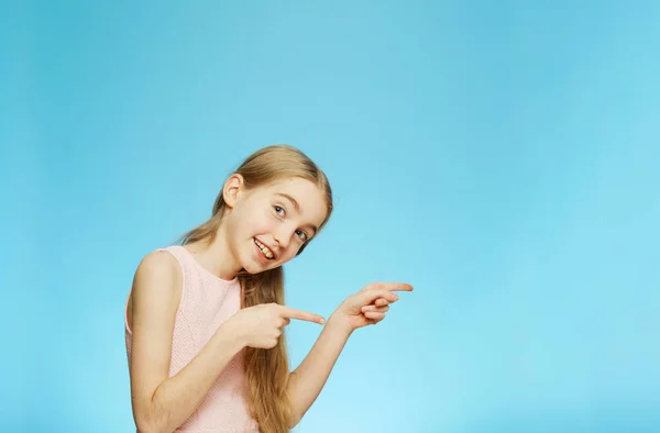 Kleines fröhliches Mädchen zeigt mit den Händen auf den leeren Raum. die Emotionen eines Kindes. — Stockfoto