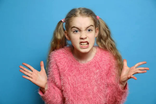 The emotions of a child. Small girl angry isolated. Beautiful little girl get angry on a blue background. Angry facial expression.