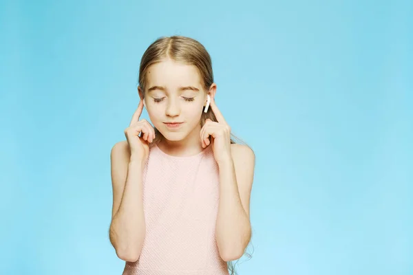 Όμορφο κοριτσάκι ακούει μουσική μέσω ασύρματων ακουστικών απομονωμένο. Το κορίτσι έκλεισε τα μάτια της, είναι ντυμένη με ελαφρύ φόρεμα.. — Φωτογραφία Αρχείου
