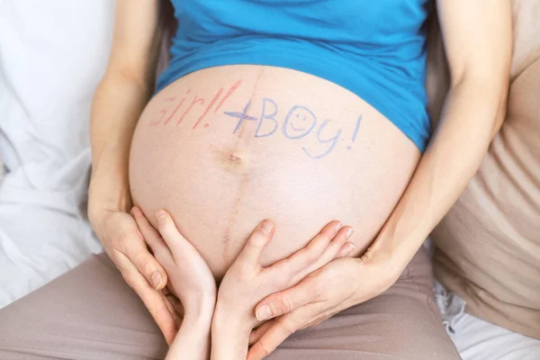 Le mani dei bambini sulla pancia di una madre incinta. gemelli in gravidanza. iscrizione Ragazza e ragazzo su una pancia incinta . — Foto Stock