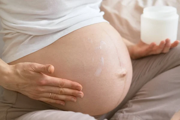 Le sbavature incinte crema di pancia. primo piano — Foto Stock