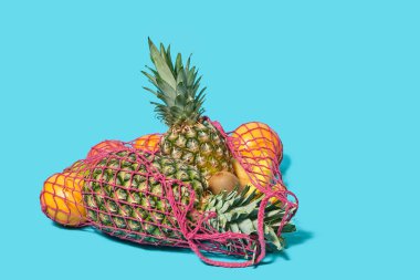 Farklı meyveler mavi arka planda bir ip torbasında yatıyor. Alışveriş ve ekoloji kavramı