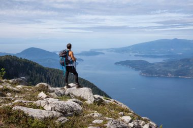 Latin Amerikalı erkek Hiker güzel manzara bakan kayalık tepe üstünde duruyor. Aslanlar Mountain, Kuzey Vancouver, British Columbia, Kanada kadar yol üzerinde gerçekleştirilen resmi.