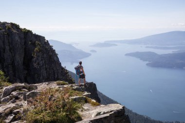 Latin Amerikalı erkek Hiker güzel manzara bakan kayalık tepe üstünde duruyor. Aslanlar Mountain, Kuzey Vancouver, British Columbia, Kanada kadar yol üzerinde gerçekleştirilen resmi.