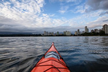 Deniz kanosu şehir manzarası içinde belgili tanımlık geçmiş ile dramatik bir gündoğumu sırasında. Vancouver, British Columbia, Kanada alınan.