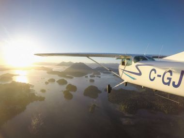 Estevan, Vancouver Adası, British Columbia, Kanada - 29 Haziran 2017 - küçük Cessna 172 uçak uçan bir parlak güneşli gün batımı sırasında Pasifik kıyısında şehir çevresinde.