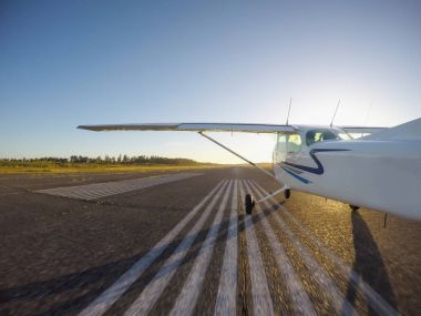 Küçük uçak bir parlak güneşli gün batımı sırasında Havaalanı pist gidiyor. Estevan, Vancouver Adası, British Columbia, Kanada alınan.