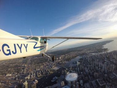 Vancouver Downtown, British Columbia, Canada - June 29, 2017 - Cessna 172 Airplane flying overtop the beautiful city during a bright sunny day. clipart