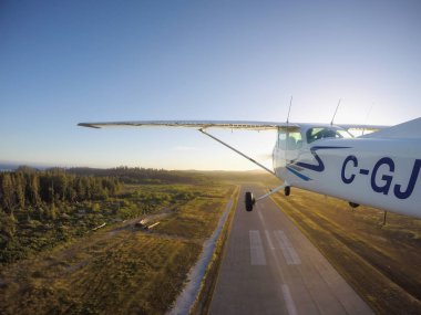 Estevan, Vancouver Adası, British Columbia, Kanada - 29 Haziran 2017 - küçük Cessna 172 uçak bir parlak güneşli gün batımı sırasında Havaalanı pist gidiyor.