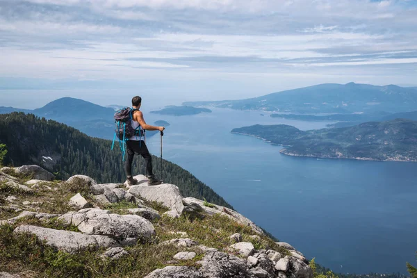 拉美男性徒步旅行者站在山顶上俯瞰美丽的风景 图片在途中被采取了到狮子山 温哥华的北部 不列颠哥伦比亚省 加拿大 — 图库照片