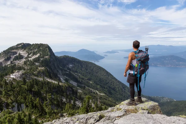Latin Amerikalı erkek Hiker güzel manzara bakan kayalık tepe üstünde duruyor. Aslanlar Mountain, Kuzey Vancouver, British Columbia, Kanada kadar yol üzerinde gerçekleştirilen resmi.