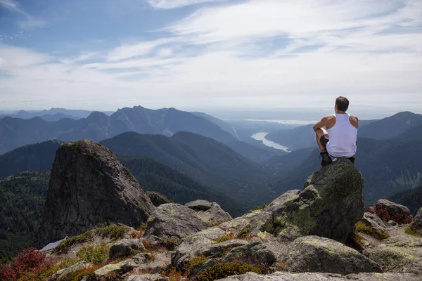 适合拉美男性徒步旅行者坐在山顶上俯瞰美丽的风景 图片在途中被采取了到狮子山 温哥华的北部 不列颠哥伦比亚省 加拿大 — 图库照片