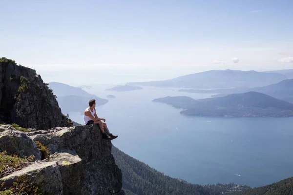 适合拉美男性徒步旅行者坐在山顶上俯瞰美丽的风景 图片在途中被采取了到狮子山 温哥华的北部 不列颠哥伦比亚省 加拿大 — 图库照片
