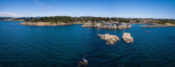 Aerial panoramic landscape view of a beautiful rocky shore on Pacific Coast. Taken in Saxe Point Park, Victoria, Vancouver Island, British Columbia, Canada.