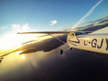North West Vancouver, British Columbia, Kanada - 30 Mart 2017 - dışında küçük bir Cessna 172 gün batımı sırasında dağların uçan uçak bakış.