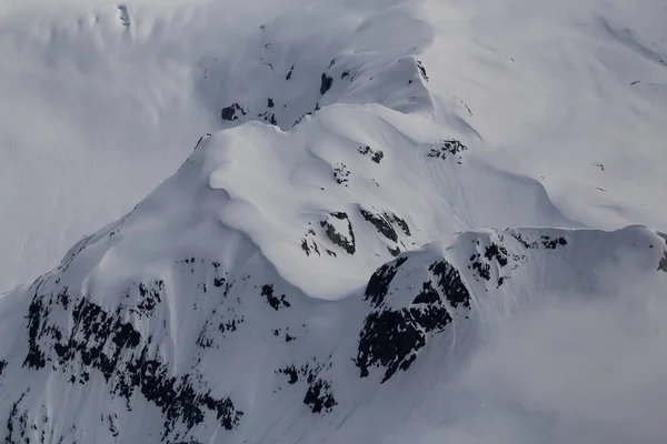 Remote Mountain Peak covered in Snow. Taken in British Columbia, Canada, from an aerial perspective.