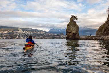 Deniz kenarındaki sete üzerinde çalışan bir adamla Stanley Park Kayak. Vancouver, British Columbia, Kanada, bulutlu kış sabahı sırasında alınan resim.