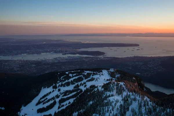 Beautiful winter sunset of Grouse Mountain with Vancouver City in the background. Picture taken from an aerial perspective in BC, Canada.
