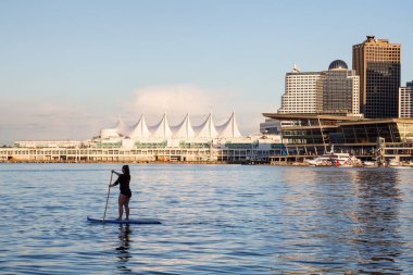 Kömür Limanı, Downtown Vancouver, British Columbia, Kanada bir stand-up kürek yönetim kurulu kız. Güzel bir gün batımı sırasında alınan.