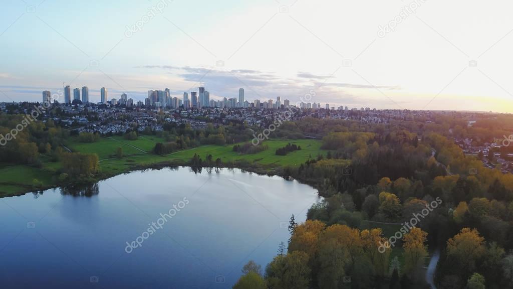 Beautiful Aerial View of Deer Lake in Burnaby, Greater Vancouver, British Columbia, Canada, with Metrotown City buildings in background. Taken during a colorful sunset.