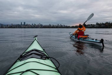 Maceracı kız arka planda şehir manzarası ile bulutlu gün doğumu sırasında Kayak. Vancouver, British Columbia, Kanada alınan.