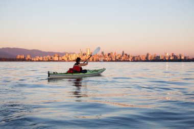Güzel kadın deniz adam şehir manzarası ile renkli ve canlı bir gün batımı sırasında okyanusta kayağı. Jericho, Vancouver, British Columbia, Kanada alınan.
