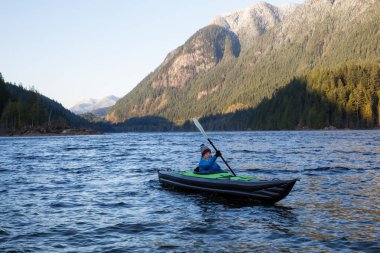 Maceracı kız güzel doğal gölde bir şişme bir kayık üzerinde kayak. Alınan Buntzen Gölü, Anmore, büyük Vancouver, Bc, Kanada.