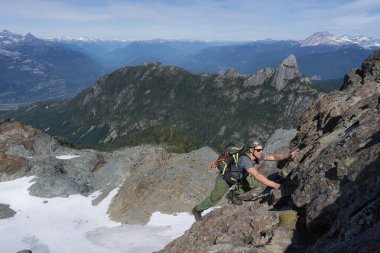 Uygun genç beyaz maceracı biri dik kaya levha bir güzel yaz günü sırasında tırmanıyor. Skypilot dağ yakınındaki Squamish, Kuzey Vancouver, Bc, Kanada için yokuş üzerinde alınan resim.