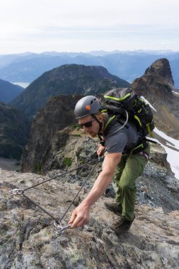Uygun genç beyaz maceracı biri dik kaya levha bir güzel yaz günü sırasında tırmanıyor. Skypilot dağ yakınındaki Squamish, Kuzey Vancouver, Bc, Kanada için yokuş üzerinde alınan resim.