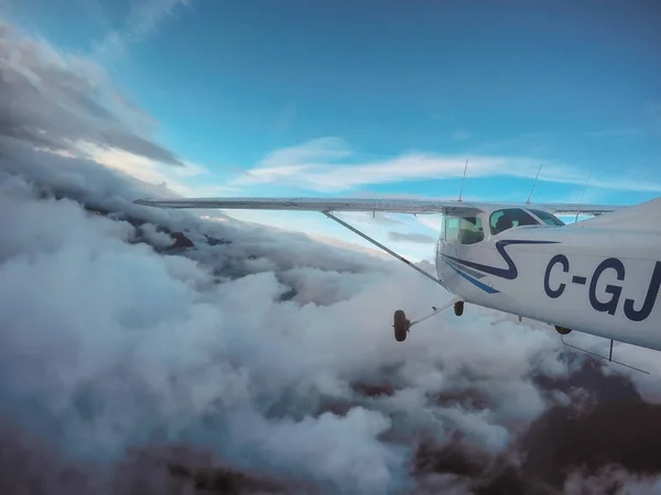 Letadlo letící v zatažené obloze kolem hory — Stock fotografie
