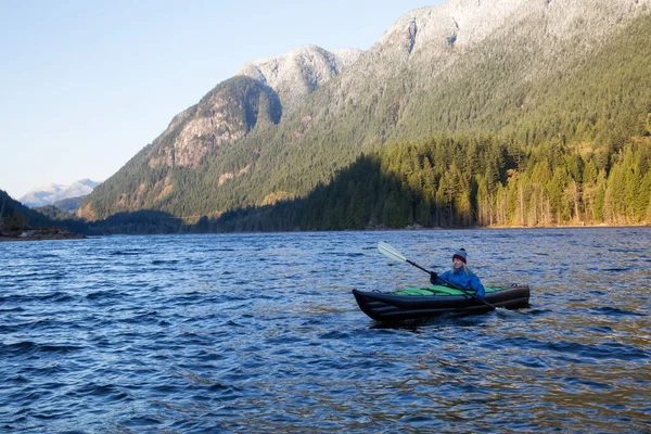 Adventurous girl is kayaking on an inflatable kayak in a beautiful natural lake. Taken in Buntzen Lake, Anmore, Greater Vancouver, BC, Canada.