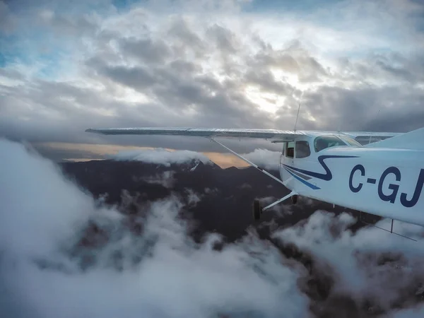 Avião voando no céu nublado em torno de montanhas Fotos De Bancos De Imagens