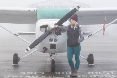 Genç beyaz kadın öğrenci Pilot havaalanında tek bir motor uçağın önünde duruyor. Pitt Meadows, Vancouver, Bc, Kanada sisli kış sabah sırasında alınan.