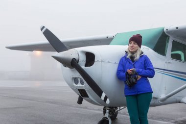 Genç beyaz kadın öğrenci Pilot havaalanında tek bir motor uçağın önünde duruyor. Pitt Meadows, Vancouver, Bc, Kanada sisli kış sabah sırasında alınan.
