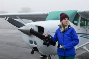 Genç beyaz kadın öğrenci Pilot havaalanında tek bir motor uçağın önünde duruyor. Pitt Meadows, Vancouver, Bc, Kanada sisli kış sabah sırasında alınan.
