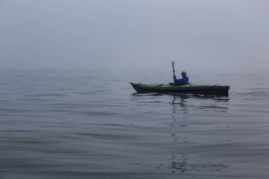 Şişme bir kayık Howe ses üzerinde bir sis sırasında Kayak kız kış akşam kaplı. Batı Vancouver, Bc, Kanada içinde alınan.