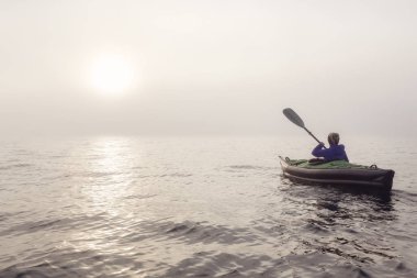 Şişme bir kayık Howe ses üzerinde bir sis sırasında Kayak kız kış günbatımı kaplı. Batı Vancouver, Bc, Kanada içinde alınan.