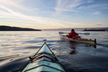 Deniz Kanosundaki Macera Adam canlı ve renkli kış günbatımında kayak yapıyor. Vancouver, British Columbia, Kanada 'da çekilmiş. Macera, Tatil Konsepti