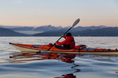 Deniz Kanosundaki Macera Adam canlı ve renkli kış günbatımında kayak yapıyor. Vancouver, British Columbia, Kanada 'da çekilmiş. Macera, Tatil Konsepti