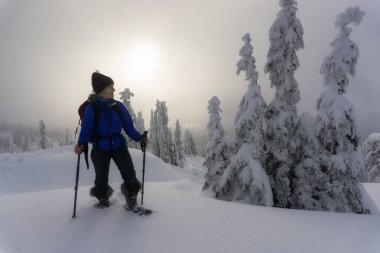 Genç maceracı Kafkas kadın karla kaplı dağlara snowshoeing. Seymour dağda, North Vancouver, British Columbia, Kanada alınan.