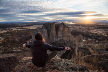 Maceracı bir meditasyon poz bir uçurumun üstünde canlı bir gün batımı sırasında oturan adam. Smith Rock, Oregon, Amerika'nın alınan. Konsept: Macera, özgürlük, seyahat, tatil, tatil