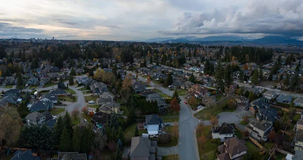 Aerial panoramic view of a suburban neighborhood during a vibrant and cloudy sunset. Taken in Greater Vancouver, British Columbia, Canada.
