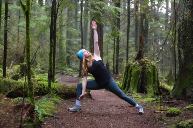 Genç beyaz kız yağmur ormanlarında yoga pratiği yapıyor. Alınan Capilano Kanyon, North Vancouver, Bc, Kanada.