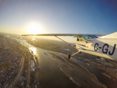 Şehrin üzerinde bir canlı kış günbatımı sırasında büyük Vancouver, British Columbia, Kanada - 22 Şubat 2018 - küçük uçak, Cessna 172, uçan.