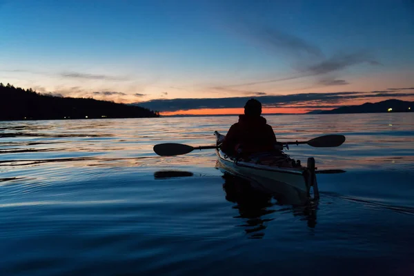 Man Kayaking on a sea kayak during a vibrant sunset. Taken near Jericho Beach, Vancouver, British Columbia, Canada.